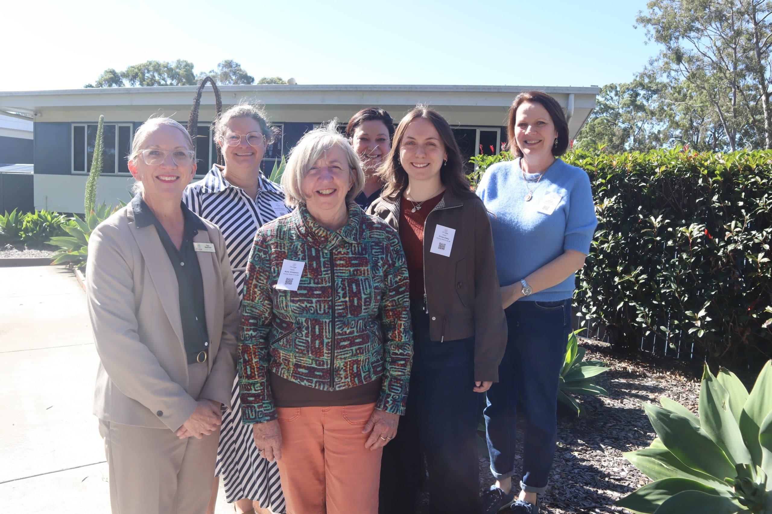 A photograph showing Toni Banfield, Raechel Smart, Associate Professor Kate Simpson, Chantall Opperman, Chloe Eddy and Hayley Mitchelson standing at the entrance of The Sycamore School